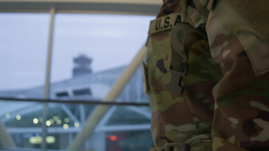 A solider in full military uniform strides through an airport their purposeful gait reflecting a sense of duty and discipline