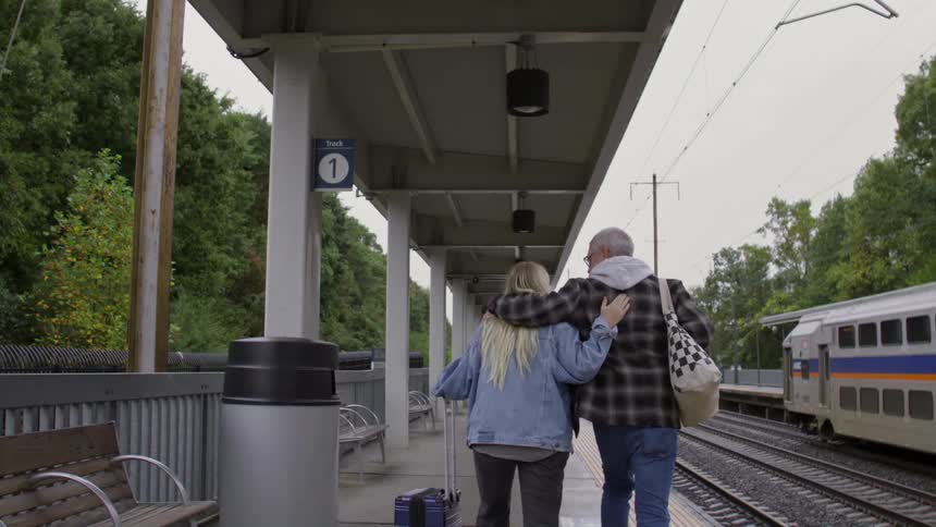 Father walking with his daughter in his arms at a train station