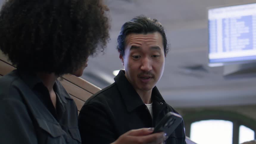 Woman interacting with a smartphone and talking to a man next to her