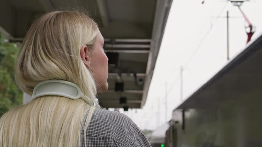 A woman stands at the station as the train rides in
