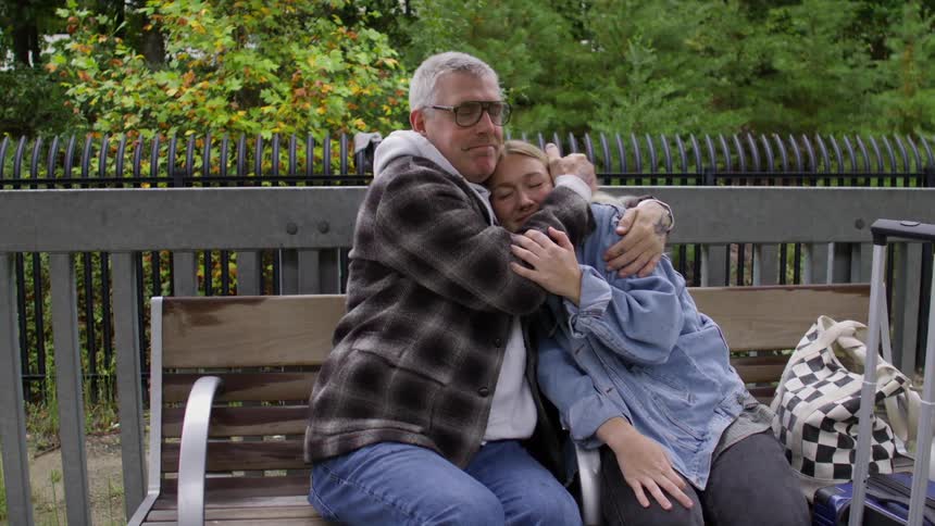 A clip of a man and a woman hugging while sitting