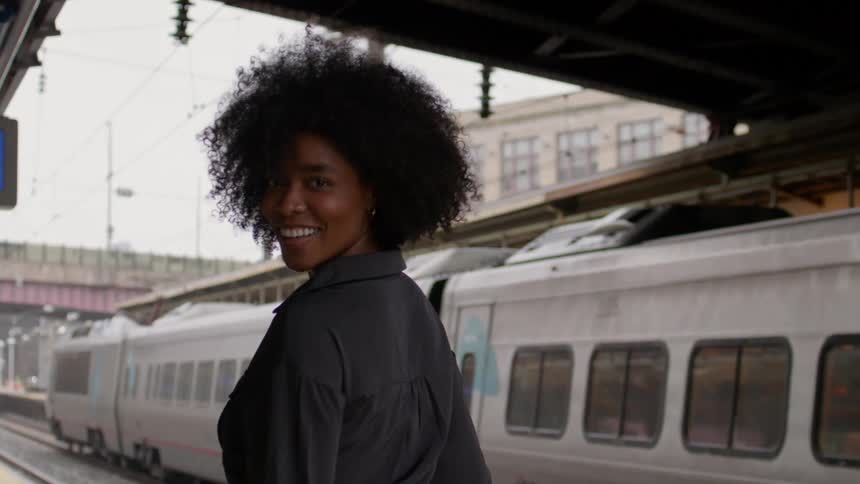 Cheerful woman walking next to a train at a terminal