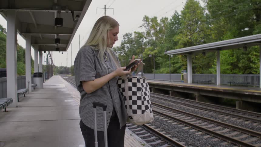 A woman answers her phone while waiting for a train