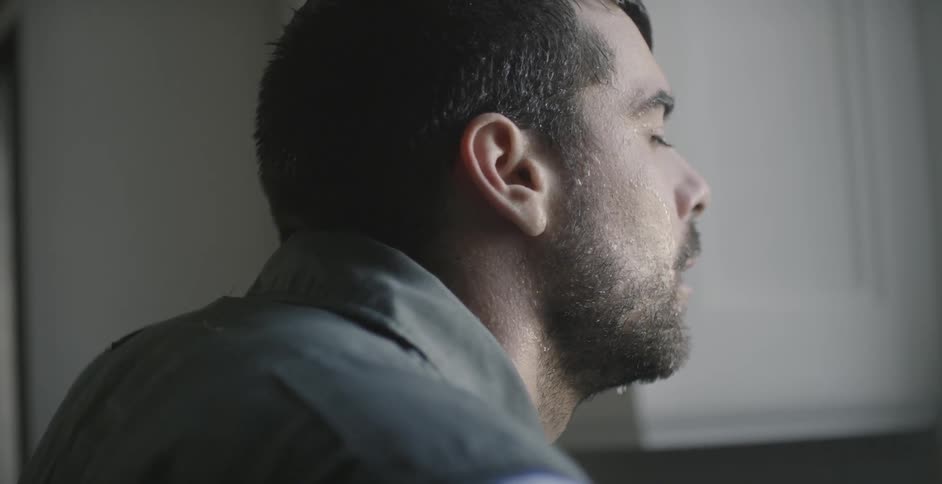 Water is dripping off a man's head as he stands in a kitchen during the day