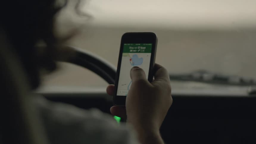 Person looks at a map on their phone in the car