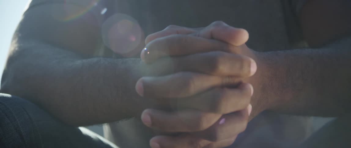 A man's hands clasped in prayer or deep thought