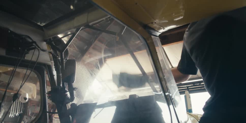A person cleaning the windows of a small airplane inside a hangar