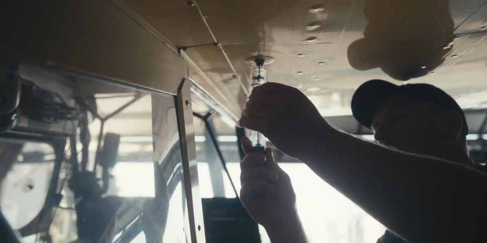 Man with a syringe testing fuel from the wing of an airplane