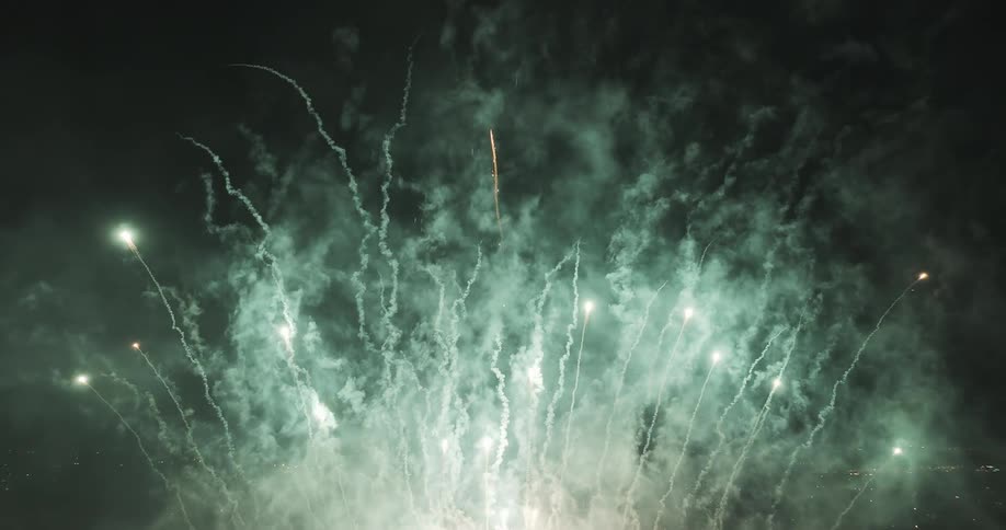 Fireworks glow as they fly into the night sky and smoke rises