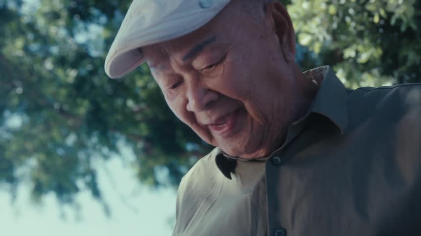 Elderly man wearing a hat is talking to someone outdoors in spring