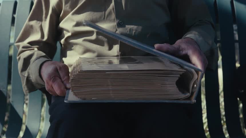 A man sits down and opens a large photo album
