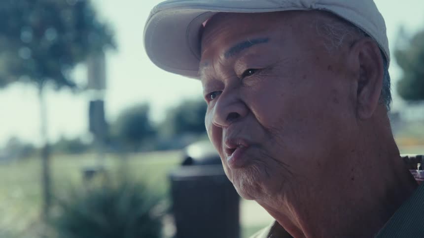 Elderly male is sitting at a park and talking to someone