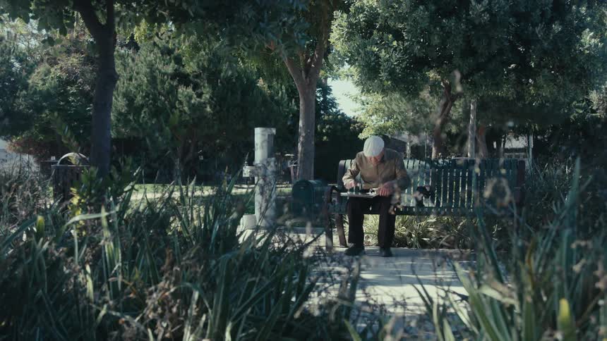 Elderly man sitting on a bench in the square