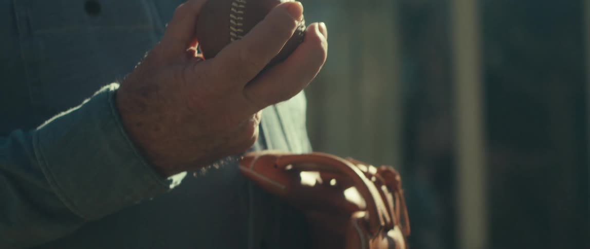 Outside of a building is a man holding a baseball and glove