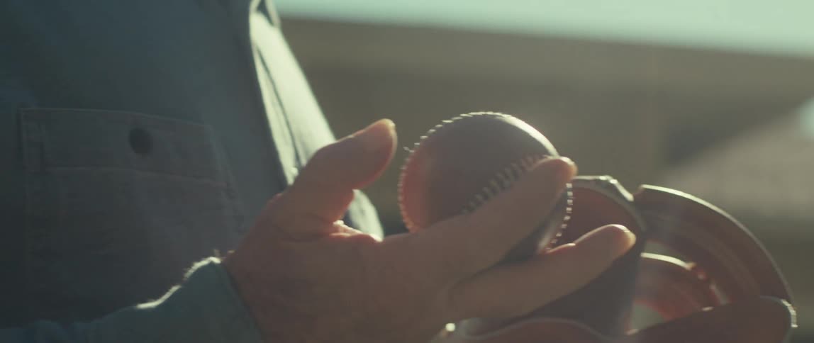 Elderly man is playing baseball outdoors on a sunny day