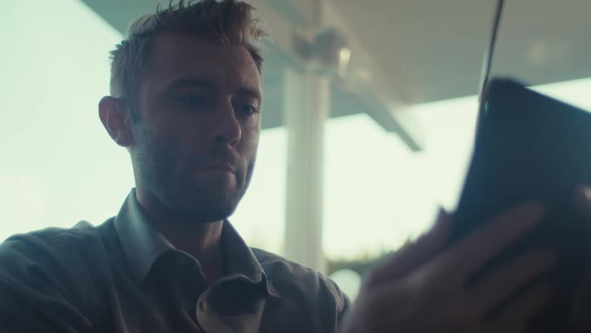 A man wearing a shirt is using a tablet for a video call