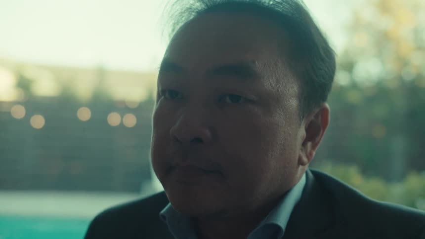 The face of an adult man wearing a suit and he is sitting and using a tablet
