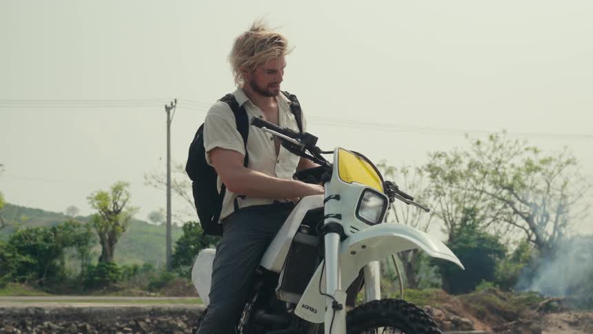 Man sitting on his motorcycle and removes his helmet