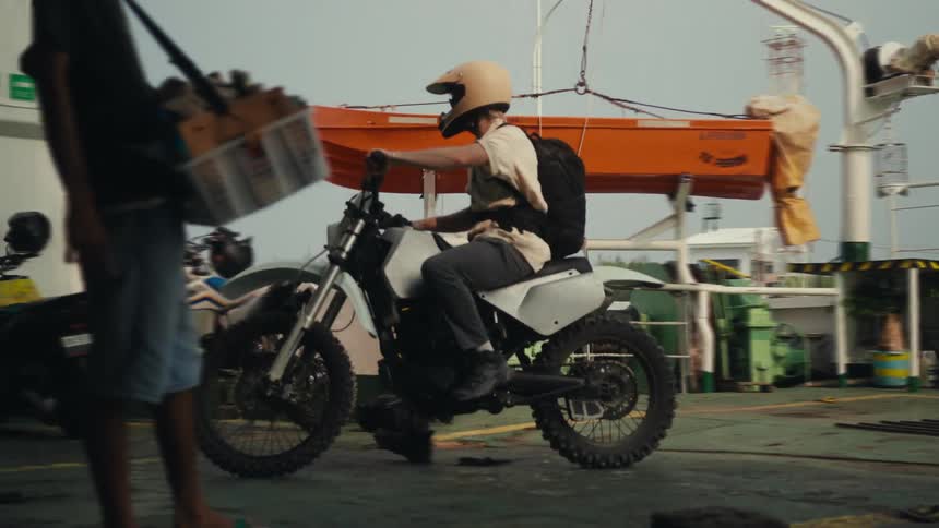 A man riding a motorcycle and wearing a yellow helmet parks it next to other motorcycles