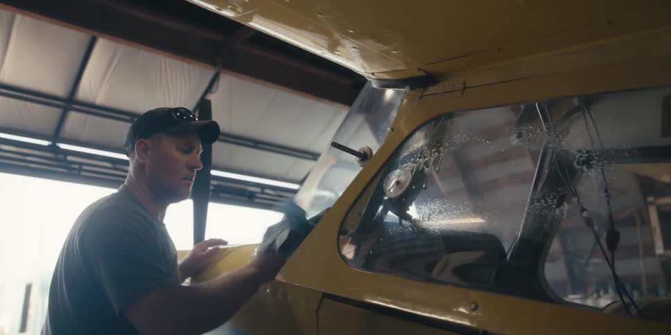 Man in cap in an indoor space cleaning airplane window