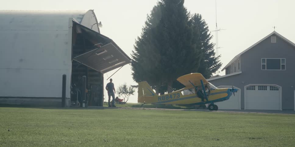 A man exits prop plane near the hangar