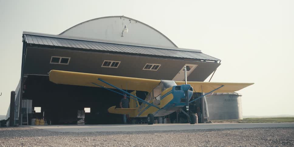 Man takes airplane out of a hangar and removes a tool from the rear tire