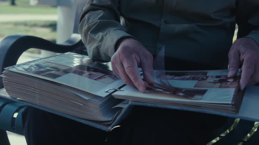 A person sits with an open photo album flipping through the pages