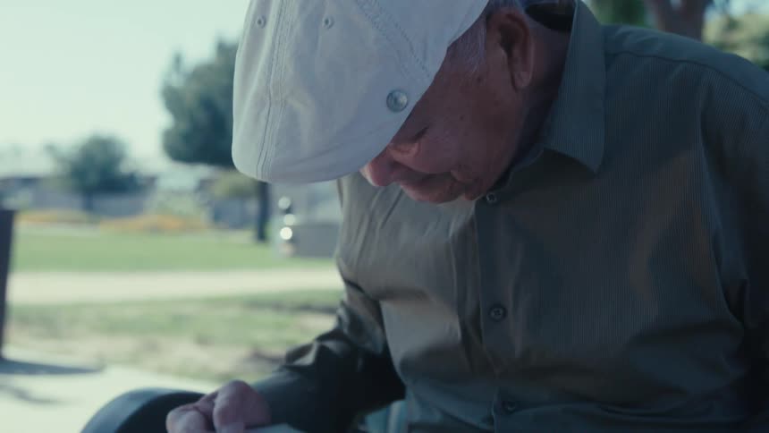 A man is smiling as he look at a photo album outside