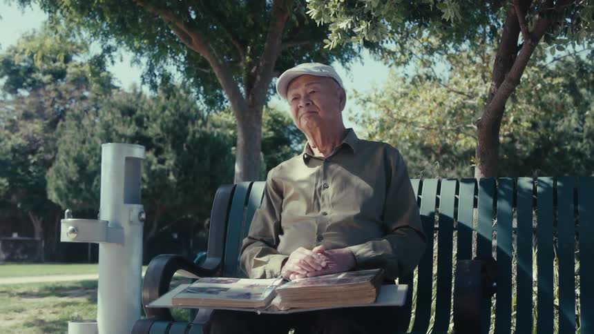 A man is smiling and sitting on a bench in the spring season