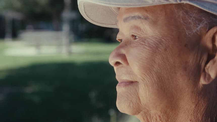A clip of an elderly man standing up in a park