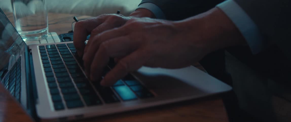 A businessmans hands use the touchpad of a laptop on the brown office couch