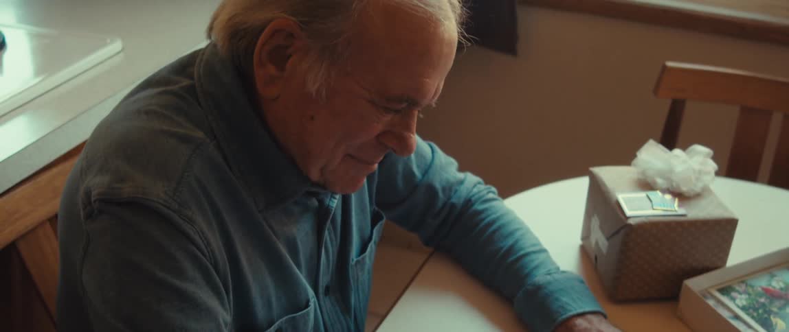 A man is writing out a card by a gift