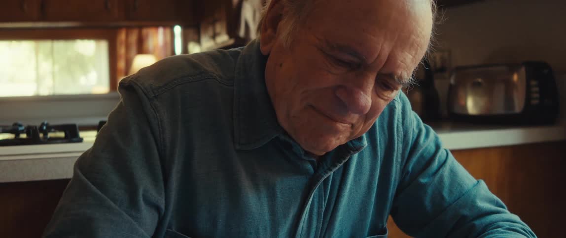 A happy elderly man feels satisfied after writing a card for a gift at home