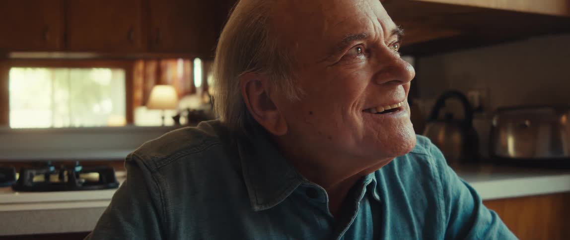 A happy smiling elderly man tears up a bit while writing a card at home