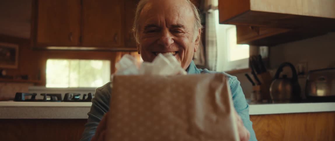 A man is smiling as he is giving out a gift
