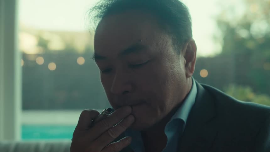 A man in a business suit sits at home thinking while using a tablet