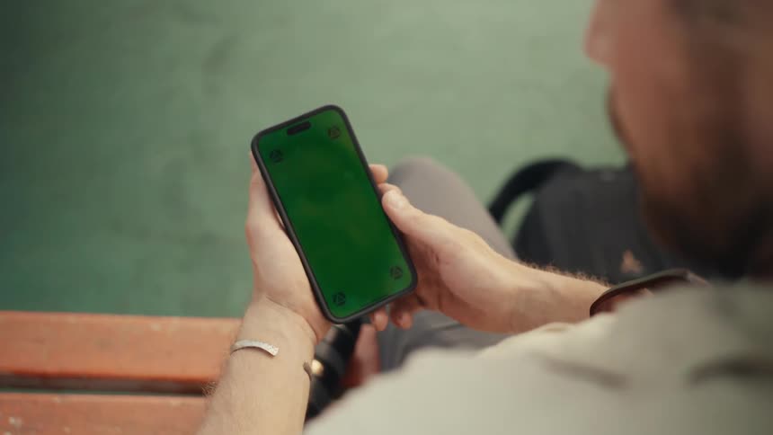 A man sits looking down at his cell phone