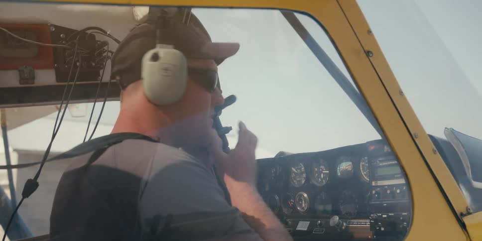 A man flying an airplane puts on headphones