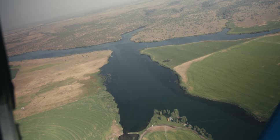 A river and farm landscape is seen from a plane flying