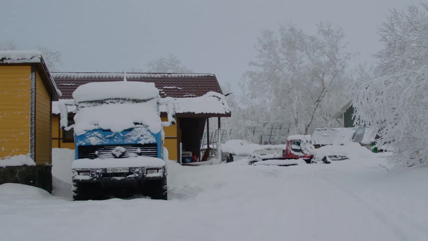 Truck next to a house in the middle of a snowy landscape