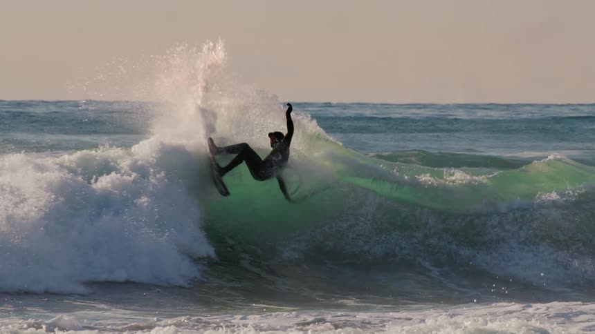 Surfer doing a maneuver on a wave in the sea