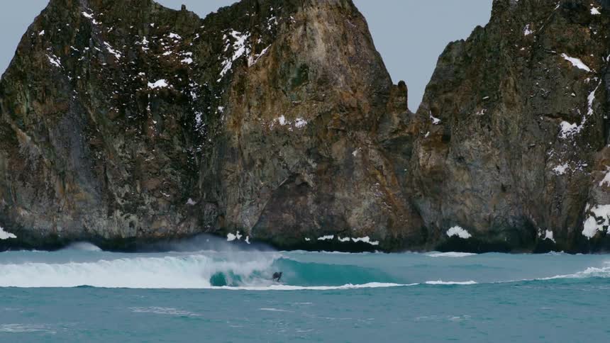 Person surfing a wave in the ocean with people on jet skis in the background