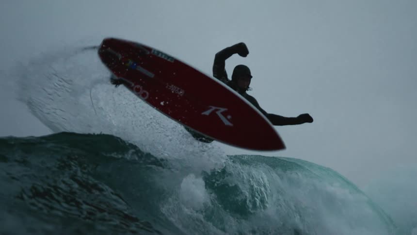 A man jumps and spins while surfing a wave