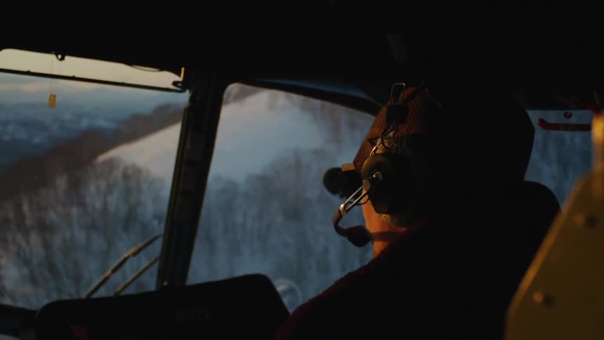 A man is flying an airplane past a snow covered mountain