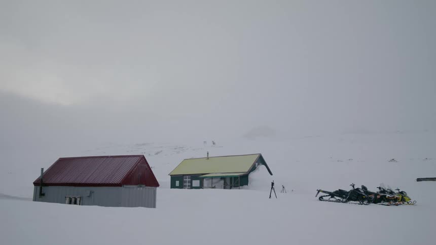 Two houses in a rural area that are completely covered in thick white snow