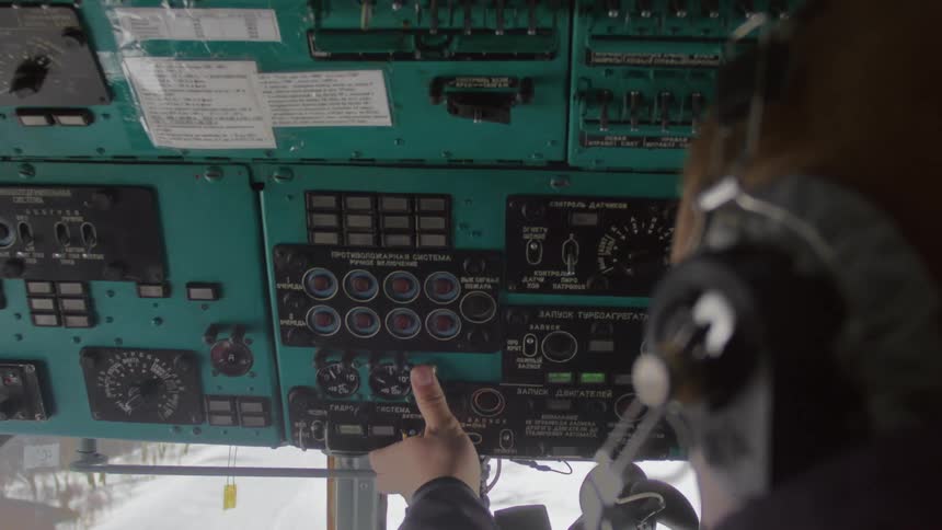 A man presses the buttons on the plane dashboard