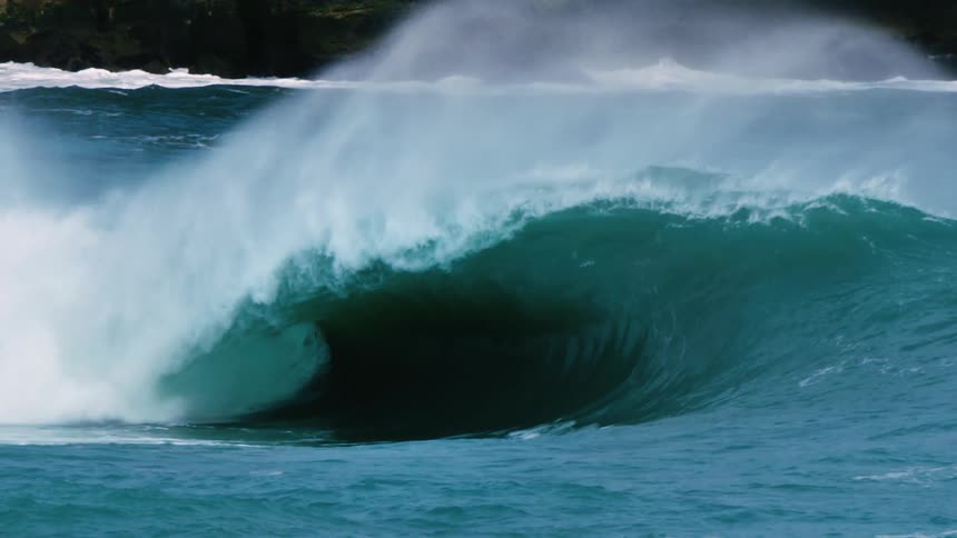Cameraman filming a large wave breaking in the ocean