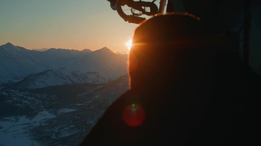 Person enjoying a mountainous landscape with the sun on the horizon