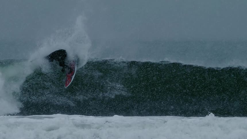 A surfer riding a wave and doing a maneuver on its crest