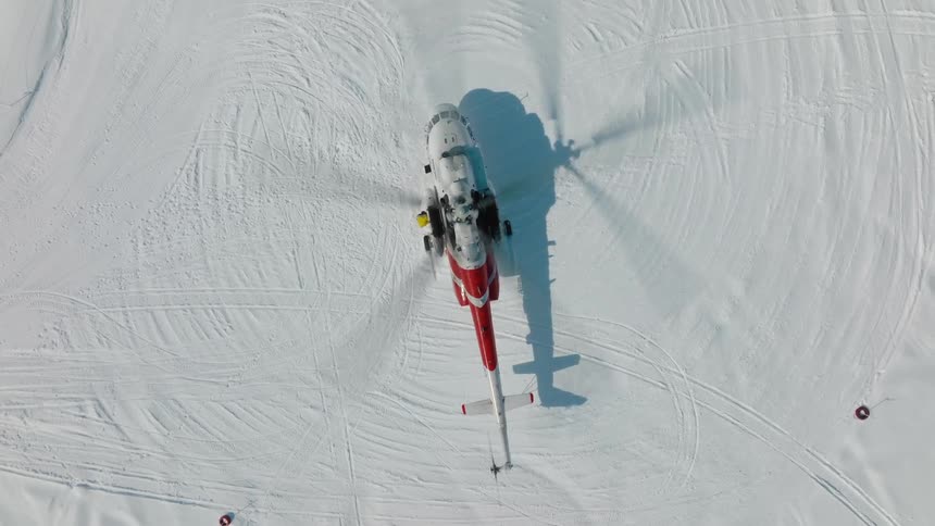 A helicopter has landed in the parking lot covered in snow